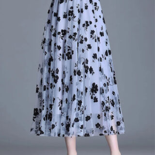 Jupe longue à motif fleuri portée par une femme dont on voit seulement les jambes.