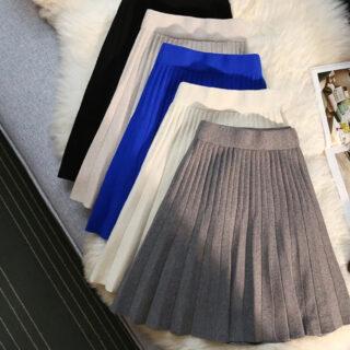 5 jupe plissées de couleurs différentes posées sur un tapis beige