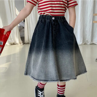 On voit le corps d'une fille qui porte une T-shirt rayé et une jupe trapèze et longue en jean.
