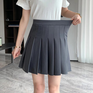 Jupe plissée grise portée par une femme en tee shirt blanc