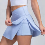 Jupe de tennis bleue avec un short portée par une femme avec un tee shirt blanc