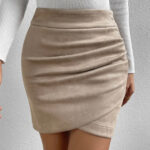 Photo d'une mini jupe beige drapée crayon portée par une femme avec un pull manches longues blanc