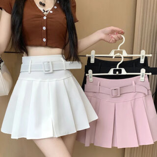 Femme portant une jupe blanche avec une ceinture et tenant deux jupes sur des ceintres.