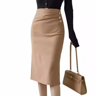Photo de jeune femme debout portant une jupe droite mi-longue marron avec un léger drapé sur la taille, un pull noir et un sac à main