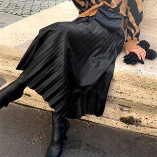 Jupe noire plissée mi-longue portée par une femme assisse