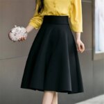 On voit le corps d'une femme blanche qui porte une jupe midi trapèze rouge.