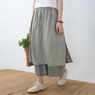 Personne portant un pantalon jupe gris avec des chaussures et un tee-shirt blanc.