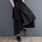 Pantalon jupe noir porté par une personne dont on voit seulement les jambes.