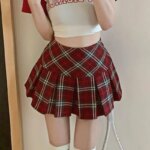 Femme portant une mini-jupe écossaise et un haut blanc.