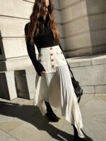 Jupe longue plissée beige asymétrique avec taille haute et des boutons dorés