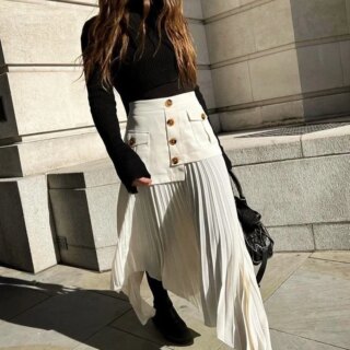 Jupe longue plissée beige asymétrique avec taille haute et des boutons dorés