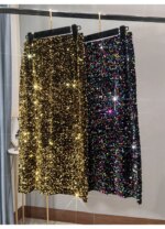 Photo de deux jupe mi-longue à sequins accrochées sur un cintre sur un portant , une dorée et une multicolore
