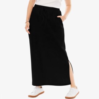 Photo d'une jupe longue de sport noir portée par une femme aecc un t-shirt blanc et des chaussures blanches.
