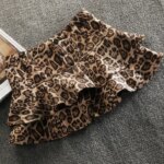 Mini-jupe léopard sur un fond gris.
