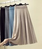 Jupe plissées beige, bleue, grise et noire suspendues à des ceintres