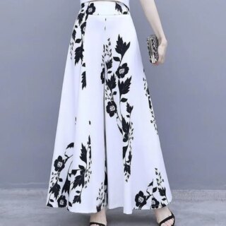 Photo représentant une jupe culotte longue blanche à fleurs portée par une femme avec une pochette dans la main gauche et des sandales noires à talons hauts