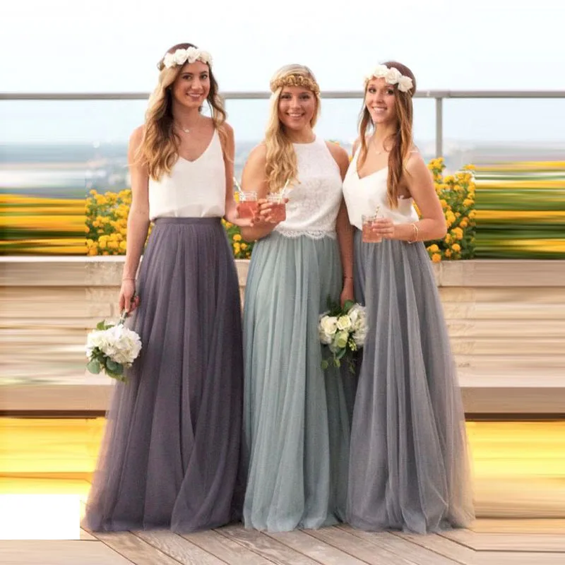 On voit trois jeunes femmes, des demoiselles d'honneur, qui portent des tenues similaires : un haut blanc et une longue jupe en tulle dans un camaïeu de gris.