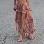 Jupe longue asymétrique avec motif floral. Portée par une femme avec des talons et un sac