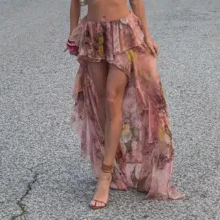 Jupe longue asymétrique avec motif floral. Portée par une femme avec des talons et un sac