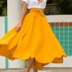 Mannequin portant une jupe légère et fluide jaune, taille haute. Elle tourne sur elle-même et donne du mouvement à la jupe.