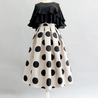 On voit une tenue sur un mannequin : une jupe blanche à pois noirs et un top à volants noirs. C'est une tenue rétro.