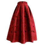Sur fond blanc, on voit une jupe rouge longueur midi, évasée. Elle est imprimée de roses rouges.