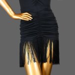On voit un mannequin qui porte une jupe noire à franges. Cette jupe est vintage et inspiré des années 30, des années folles.