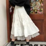 Jupe Longue Blanche Taille Haute Ajustable portée par une femme à l'entrée d'une maison