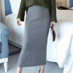 Jupe Laine Moulante et Tendance portée par une femme avec un sac dans une chambre avec un lit derrière