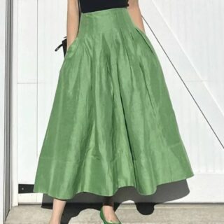 Jupe Verte Longue Évasée avec Taille Haute portée par une femme avec un haut noir en extérieur