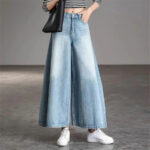 Pantalon Jupe Jean Surdimensionné Style Vintage porté par une femme avec un sac sur fond gris