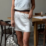 Jupe Blanche et Sexy en Satin sur une femme devant une table